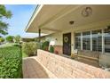 Charming covered front porch with brick accents, a decorative wreath, and cozy seating, perfect for relaxing outdoors at 10002 W Shasta Dr, Sun City, AZ 85351