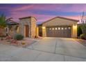 Charming single-story home with a stone accent wall, desert landscaping, a two-car garage, and a beautiful sunset backdrop at 12663 W Pinnacle Vista Dr, Peoria, AZ 85383