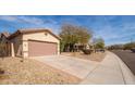 Home exterior showcasing a spacious driveway, desert landscaping, and mountain views at 17560 W East Wind Ave, Goodyear, AZ 85338