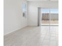 Bright living room with neutral tile flooring and sliding glass doors to the backyard at 25449 W Graham Trl, Buckeye, AZ 85326