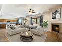 Inviting living room featuring a fireplace, ceiling fan, and a smooth transition to the kitchen area at 3410 E Pageant Pl, Gilbert, AZ 85297