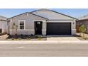Charming single-story home featuring a gray facade, black door, and a two-car garage at 3806 N Camden Dr, Florence, AZ 85132