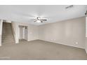 Spacious living room with neutral carpet, fan, and a staircase to the second level at 42015 W Hillman Dr, Maricopa, AZ 85138