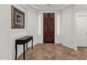 Elegant entryway with a dark wood door, beautiful tile flooring and white walls at 5032 W Yearling Rd, Phoenix, AZ 85083