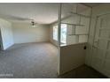 Open living room featuring neutral carpet, a bright window, and a partial divider wall with built-in shelving at 6132 E Decatur St, Mesa, AZ 85205