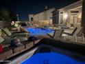 Nighttime view of a luxurious pool and hot tub surrounded by lounge chairs at 8041 E Teton Cir, Mesa, AZ 85207