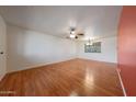 Bright living room featuring hardwood floors, ceiling fan, and large window providing natural light at 10650 W Riviera Dr, Sun City, AZ 85351