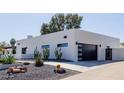 Modern home featuring a sleek garage door and desert landscaping, with cactus at 12236 N 59Th St, Scottsdale, AZ 85254