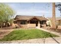 Charming single-story home showcases a lush front yard with mature trees and manicured landscaping at 130 W Palm Ln, Phoenix, AZ 85003