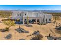 Desert modern home with pristine white exterior, desert landscaping, covered patio, and picturesque mountain views at 13502 E Jomax Rd, Scottsdale, AZ 85262