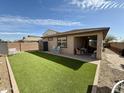 Well-maintained backyard with artificial turf, a covered patio, and privacy fencing at 14296 W Surrey Dr, Surprise, AZ 85379