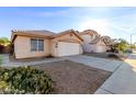 Attractive single-story home featuring a neutral stucco facade, tile roof, desert landscaping and long driveway at 15601 W Hammond Dr, Goodyear, AZ 85338