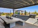 Outdoor barbecue area with built-in grill and dining table under a shaded pergola at 16020 W Desert Hollow Dr, Surprise, AZ 85387