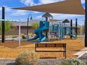 Community playground with slides, climbing structures, bench seating and shade structure at 16076 W Prickly Pear Trl, Surprise, AZ 85387