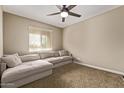 Comfortable bedroom featuring neutral carpet, a large window, ceiling fan, and a plush sectional sofa at 25907 N 134Th Dr, Peoria, AZ 85383