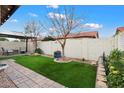 Lush backyard with artificial turf, a shaded seating area, and mature trees for added privacy at 542 S Higley Rd # 83, Mesa, AZ 85206