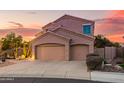 Two-story home with a three-car garage and desert landscaping at dusk at 9812 E Karen Dr, Scottsdale, AZ 85260