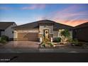 Beautiful home with landscaped front yard, brick driveway, and warm exterior lighting at sunset at 18961 N 259Th Ave, Buckeye, AZ 85396