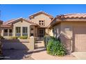 Welcoming front entrance with security gate, desert landscaping, and charming architectural details at 19824 N Valencia Ct, Surprise, AZ 85374