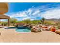 Beautiful pool and spa surrounded by desert landscaping, rock features, and lounge chairs under a bright sky at 24548 N 121St Pl, Scottsdale, AZ 85255