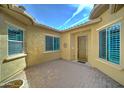 Private courtyard featuring a tiled patio, stucco walls, and windows with blue shutters at 26439 W Covey Ln, Buckeye, AZ 85396
