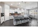 Gourmet kitchen features white cabinets, granite countertops, stainless steel appliances, an island, and modern lighting at 31660 N 130Th Ln, Peoria, AZ 85383