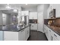 Gourmet kitchen features white cabinets, granite countertops, stainless steel appliances, an island, and modern lighting at 31660 N 130Th Ln, Peoria, AZ 85383