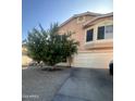 Two story beige home with a healthy citrus tree, two car garage and desert landscaping at 8863 W Greer Ave, Peoria, AZ 85345