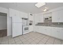 This kitchen features white cabinets, appliances, tile floors and granite countertops at 11223 W Missouri Ave, Youngtown, AZ 85363