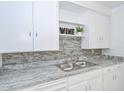 Up close view of kitchen showcasing granite counters and grey brick backsplash at 11223 W Missouri Ave, Youngtown, AZ 85363