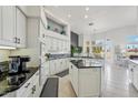 Modern white kitchen with black granite countertops, tile flooring, stainless steel appliances, and a center island at 14110 W Robertson Dr, Sun City West, AZ 85375