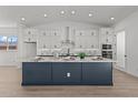 Stylish kitchen boasts white cabinets, granite countertops, stainless appliances, and a large navy blue island at 32489 N 135Th Dr, Peoria, AZ 85383