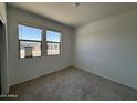 Bright bedroom featuring neutral carpet, white walls and large windows allowing ample natural light at 46886 W Old Timer Rd, Maricopa, AZ 85139