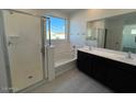 Bright bathroom with a walk-in shower, soaking tub, double vanity, and a large window at 7418 W Rovey Ave, Glendale, AZ 85303