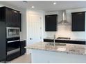 Modern kitchen featuring granite countertops, black cabinets, stainless steel appliances, and a large kitchen island at 7418 W Rovey Ave, Glendale, AZ 85303