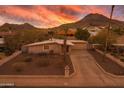 Charming single-story home features a desert landscape, an attached garage, and mountain views under a vibrant sunset at 9031 N 14Th St, Phoenix, AZ 85020