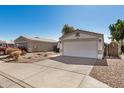 A house with a two-car garage, desert landscaping, and a long driveway, surrounded by other houses at 1345 W Diamond Ave, Apache Junction, AZ 85120