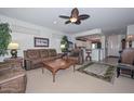 Cozy living room featuring a ceiling fan, leather furniture, and an open layout to the kitchen at 15779 W Remington Dr, Surprise, AZ 85374