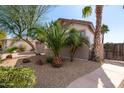 Landscaped view of the home showing the detached garage, gravel groundcover, and manicured shrubs and trees at 18261 W Weatherby Dr, Surprise, AZ 85374