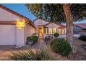 Inviting single-story home with a two-car garage, well-lit entryway, and mature landscaping at 20113 N Lagos Ct, Surprise, AZ 85374