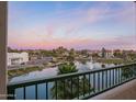 Balcony view of the pond with a fountain, trees, nearby buildings, and a colorful sky at 2511 W Queen Creek Rd # 307, Chandler, AZ 85248