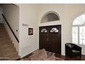 Bright foyer with dark wood double doors, high ceilings, and staircase leading upstairs at 5879 E Marconi Ave, Scottsdale, AZ 85254