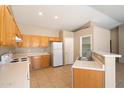 Well-lit kitchen features tile floors, light wood cabinets, white appliances, and a breakfast bar overlooking the living area at 1301 N Jackson St, Chandler, AZ 85225