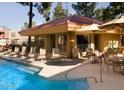 Inviting community pool with lounge chairs and tables with chairs under umbrellas for relaxing by the water at 17211 N 35Th Ave # 1035, Phoenix, AZ 85053