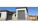 View of gray multi-car garage with carriage doors and exterior lighting on a sunny day at 17312 W Royal Palm Rd, Waddell, AZ 85355