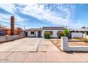 Exterior shot showing a well-maintained home with a long driveway, quaint front yard, and decorative chimney at 3129 W Pierce St, Phoenix, AZ 85009