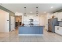 Modern kitchen with a center island, white cabinets, stainless steel appliances, and stylish pendant lighting at 40176 W Williams Way, Maricopa, AZ 85138