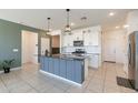 Modern kitchen with a center island, white cabinets, stainless steel appliances, and stylish pendant lighting at 40176 W Williams Way, Maricopa, AZ 85138