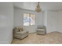 Cozy living room with neutral-toned chairs, tiled floors, and a stylish chandelier at 1016 E Saddleback Pl, San Tan Valley, AZ 85143