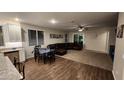 Open-concept living area with wood-look tile flooring, brown leather couches, and dining table with seating at 13487 W Buckskin Trl, Peoria, AZ 85383